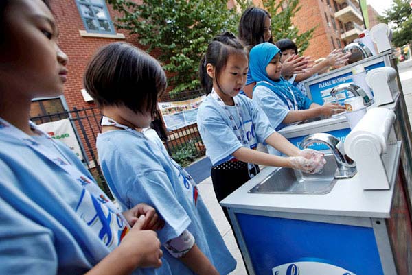 BETTER SOCIETY: children gathered at hand-washing stations learning about cleanliness and hygiene habits.